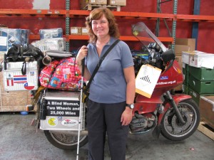 Picture of Cathy standing in front of Bertha at the air freight warehouse with all of our equipment strapped onto the seat.  