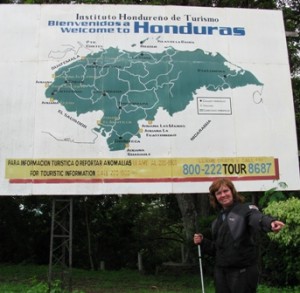 Picture of CAthy standing underneath a large bill-board showing a map of Honduras. She is pointing towards the direction we are about to set off.