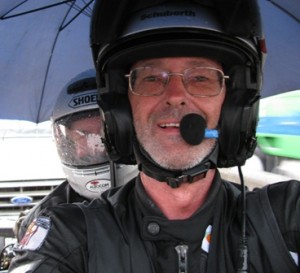 Picture of Bernard and CAthy sitting on the bike sheltering under the umbrella at the USA border before crossing.